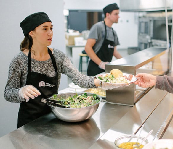 camp staff serve a plate of food